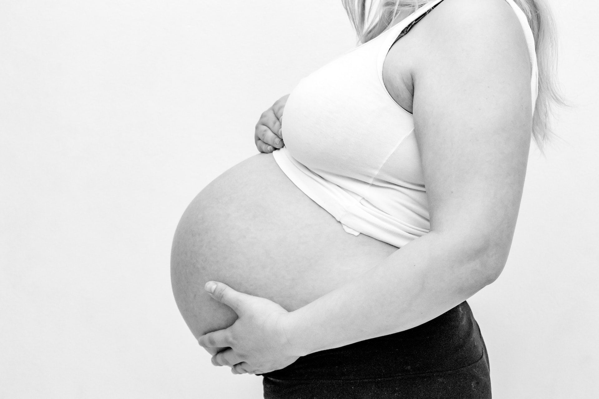black and white photo of a pregnant woman holding her stomach